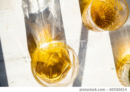 Whiskey in glasses on table in bright sunlight, yellow drink Whiskey in glasses on table in bright sunlight, yellow drink 60580814