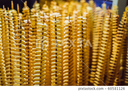 Spiral potatoes fried, on wooden sticks, spiral. Selling food at the market. Unhealthy fried food. Street food, a spiral fried potato on a stick 60581126