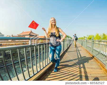 Enjoying vacation in China. Young woman with national chinese flag in Forbidden City. Travel to China concept. Visa free transit 72 hours, 144 hours in China 60582527