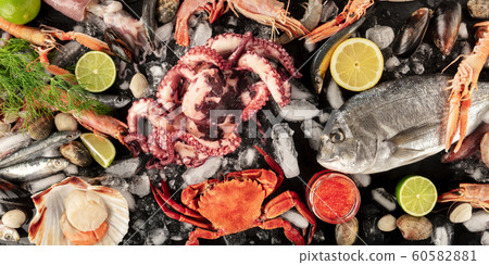 Fish and seafood panorama, a flat lay top shot on a dark background. Fresh sea bream. shrimps, crab, sardines, squid, mussels, octopus, scallops and caviar 60582881