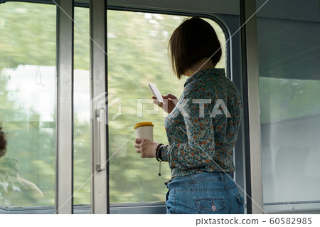 Dark-haired woman in a shirt with a phone in her hand 60582985