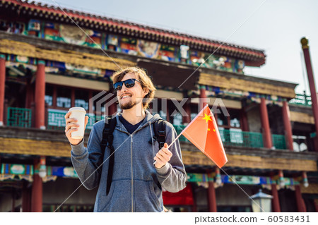 Enjoying vacation in China. Young man with national chinese flag on the background of the old Chinese street. Travel to China concept. Visa free transit 72 hours, 144 hours in China 60583431