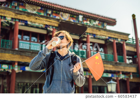Enjoying vacation in China. Young man with national chinese flag on the background of the old Chinese street. Travel to China concept. Visa free transit 72 hours, 144 hours in China 60583437