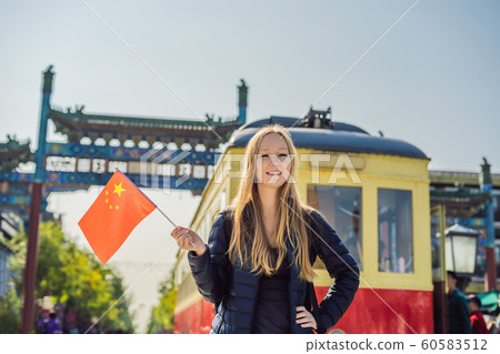 Enjoying vacation in China. Young woman with national chinese flag on the background of the old Chinese street. Travel to China concept. Visa free transit 72 hours, 144 hours in China 60583512