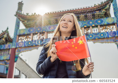 Enjoying vacation in China. Young woman with national chinese flag on the background of the old Chinese street. Travel to China concept. Visa free transit 72 hours, 144 hours in China 60583524