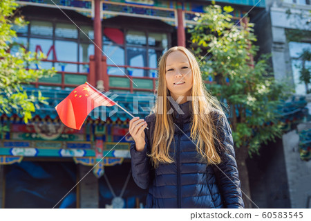 Enjoying vacation in China. Young woman with national chinese flag on the background of the old Chinese street. Travel to China concept. Visa free transit 72 hours, 144 hours in China 60583545