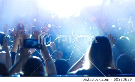 Energetic people dancing with their hands up at the rock concert and recording on the phone - blue lighting Energetic people dancing with their hands up at the rock concert and recording on the phone - blue lighting 60583659