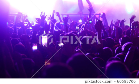 Energetic people dancing with their hands up at the punk concert - purple lighting Energetic people dancing with their hands up at the punk concert - purple lighting 60583706