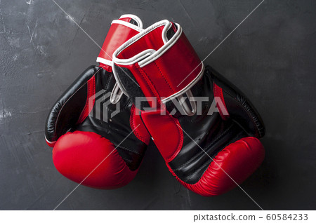 Red boxing gloves hang on the gray wall 60584233