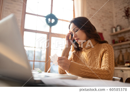 Dark-haired young woman in sweater looking at the bill 60585378