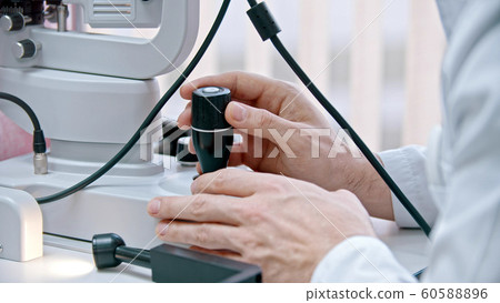 Ophthalmology treatment - a young woman checking her visual acuity with a machine - control the machine with a lever arm 60588896