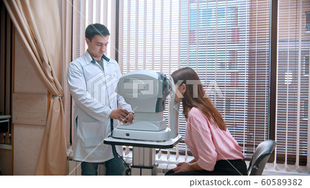 Ophthalmology treatment - young woman checking her visual acuity with a special equipment Ophthalmology treatment - young woman checking her visual acuity with a special equipment 60589382