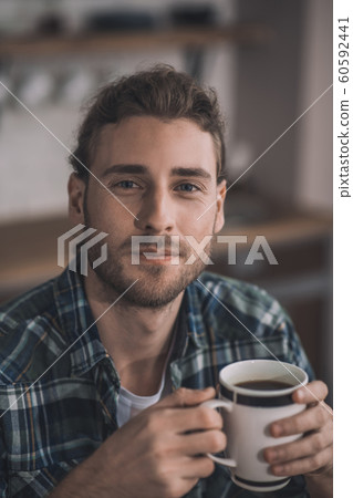 Handsome long-haired man drinking his morning coffee Handsome long-haired man drinking his morning coffee 60592441