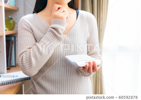 A woman who calculates with a calculator A woman who calculates with a calculator 60592878