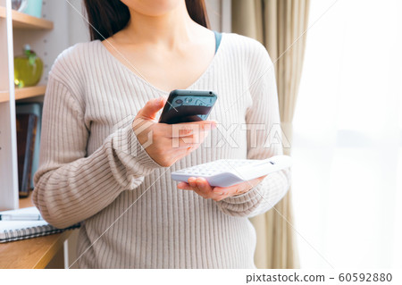 A woman who calculates while looking at a smartphone 60592880