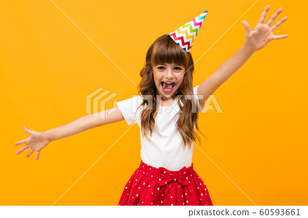 cute happy girl with a bright festive cap in a skirt on a yellow background 60593661