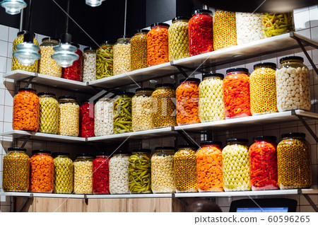 Various jars with Home Canning Fruits and Vegetables jam on glass shelves 60596265