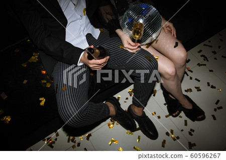 Legs of young couple toasting with flutes of champagne while resting on couch Legs of young couple toasting with flutes of champagne while resting on couch 60596267