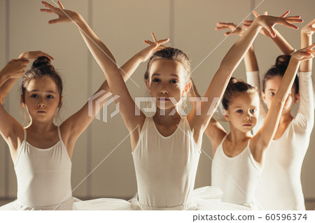 Adorable caucasian little girls dressed as a ballerina in white tutu in studio 60596374