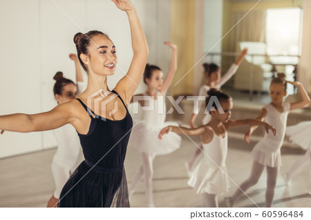 young female ballerina show right pose to kids in studio 60596484