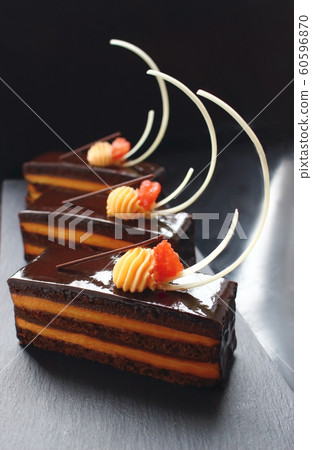 Orange Opera cake slices with citrus ganache and white chocolate decorations 60596870