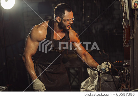 handsome man work on a blacksmith with metal handsome man work on a blacksmith with metal 60597396