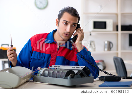 Young repairman repairing air-conditioner at warranty center Young repairman repairing air-conditioner at warranty center 60598123