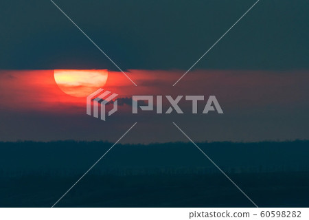 Dramatic sunset sky with dark clouds and red sun Dramatic sunset sky with dark clouds and red sun 60598282