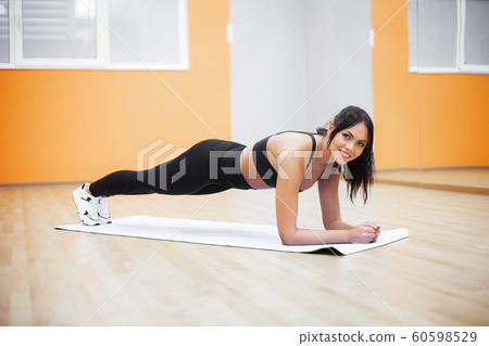 Young beautiful woman doin pushups in the gym. Fitness girl workout in the gym 60598529