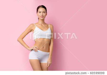 Happy young female with beautiful slim body in white sport clothes - isolated on pink background Happy young female with beautiful slim body in white sport clothes - isolated on pink background 60599099
