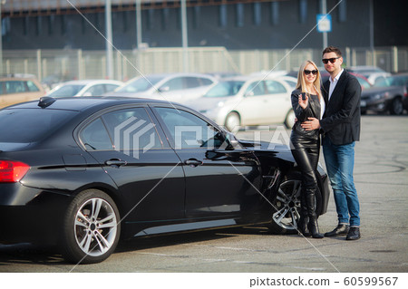 The successful visit to the dealership. Happy young couple chooses and buying a new car for the family The successful visit to the dealership. Happy young couple chooses and buying a new car for the family 60599567