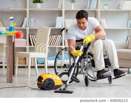Disabled man with vacuum cleaner at home 60600223