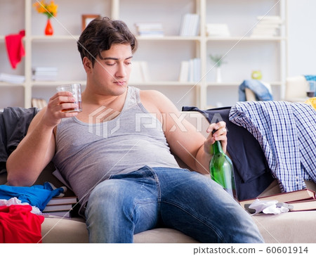 Young man student drunk drinking alcohol in a messy room Young man student drunk drinking alcohol in a messy room 60601914