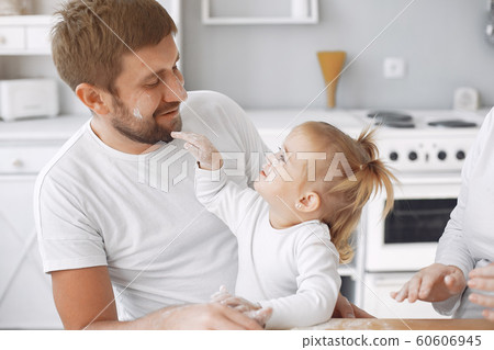 Family sitting in a kitchen and cook the dough for cookies Family sitting in a kitchen and cook the dough for cookies 60606945