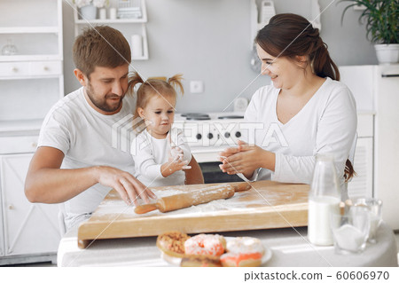 Family sitting in a kitchen and cook the dough for cookies 60606970