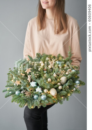 Small arrangement of fresh spruce in a wicker basket. Christmas mood. Beautiful bouquet in womans hands.. 60609406