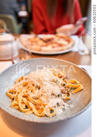 Woman eats Italian pasta with duck. Closeup tagliatelle wind it around a fork with a spoon. Parmesan cheese Woman eats Italian pasta with duck. Closeup tagliatelle wind it around a fork with a spoon. Parmesan cheese 60610503