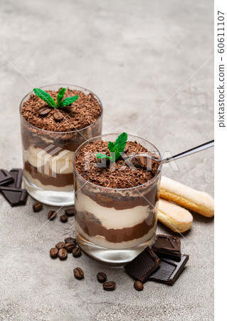 Classic tiramisu dessert in a glass cup, savoiardi cookies and pieces of chocolate on concrete background 60611107