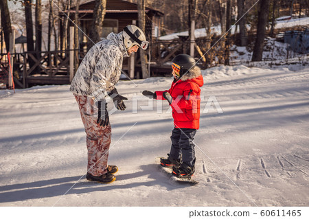 Dad teaches son snowboarding. Activities for children in winter. Children's winter sport. Lifestyle 60611465