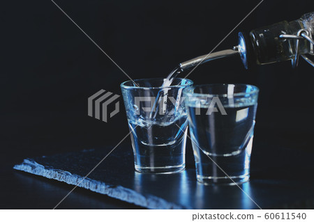 bottle of vodka is poured into a glass 60611540