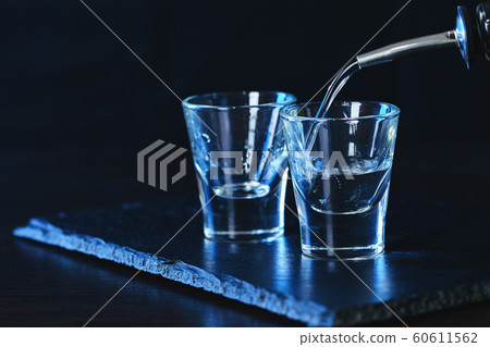 bottle of vodka is poured into a glass 60611562