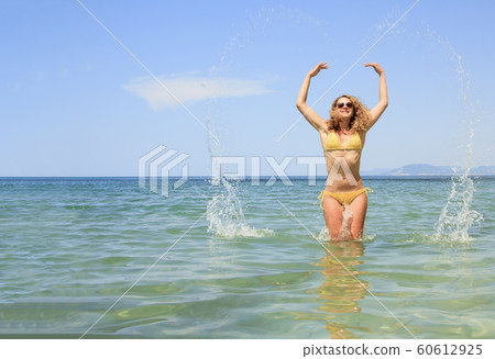 Beautiful woman jumping out of the sea leaving a 60612925