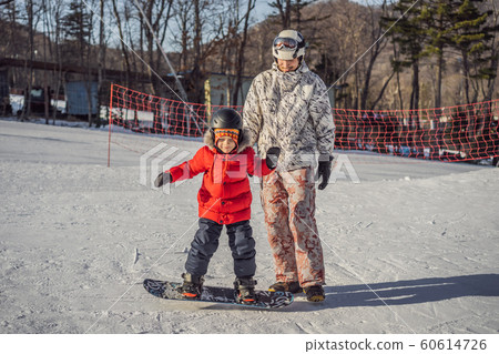 Dad teaches son snowboarding. Activities for children in winter. Children's winter sport. Lifestyle 60614726