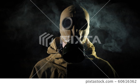 A man in a protective suit and gas mask, smoke in the foreground 60616362