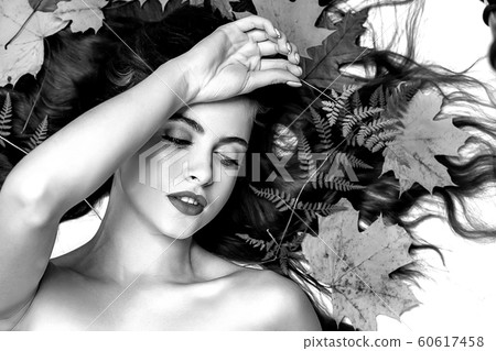 Portrait of a young brunette woman on a white background with a green fern and yellow leaves around her head Portrait of a young brunette woman on a white background with a green fern and yellow leaves around her head 60617458