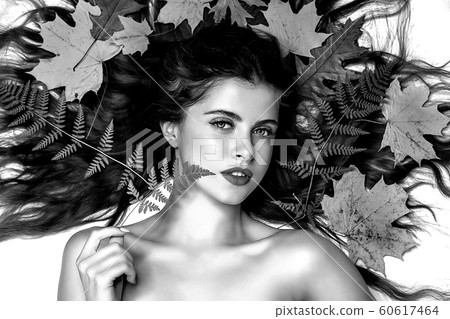 Portrait of a young brunette woman on a white background with a green fern and yellow leaves around her head Portrait of a young brunette woman on a white background with a green fern and yellow leaves around her head 60617464