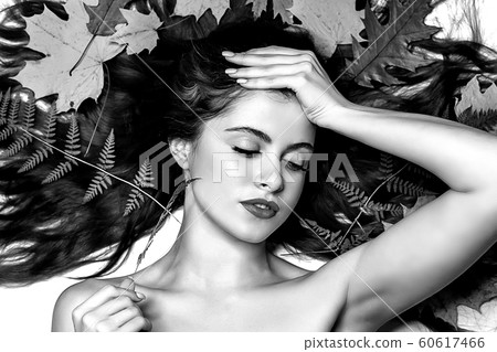Portrait of a young brunette woman on a white background with a green fern and yellow leaves around her head Portrait of a young brunette woman on a white background with a green fern and yellow leaves around her head 60617466