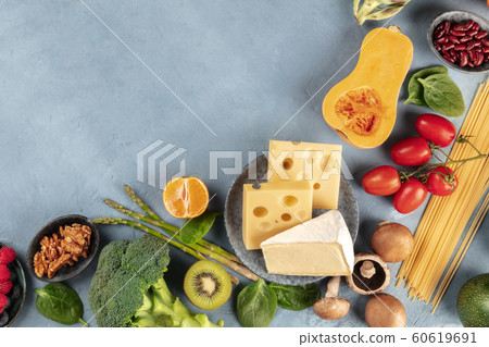 Vegetarian food background. An overhead shot of fruits, vegetables, cheese, mushrooms, and pasta, nuts and legumes, with a place for text 60619691