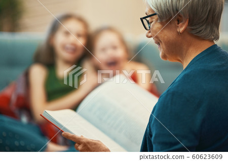 Grandmother reading a book to granddaughters Grandmother reading a book to granddaughters 60623609