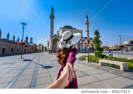 Women tourists holding man's hand and leading him to mosque in Konya, Turkey. 60625913